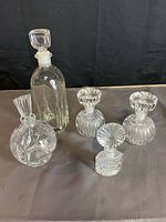 Front view of all five glass decanters on a grey surface with black background