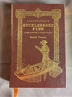Front cover image showing brown leather cover with gold embossed title and illustration of boy on boat.