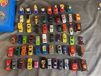Top view of approximately 49 assorted miniature cars including various colors and types arranged on a surface.