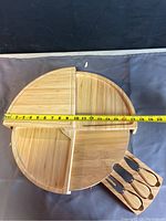 Round bamboo charcuterie tray measuring approximately 12 inches in diameter with three divided sections and three bamboo-handled utensils placed beside it.