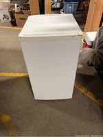 White Sanyo mini fridge closed viewed from top front corner showing compact design.