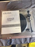 Turntable under clear plastic lid with manual placed on top showing Scott brand and model PS68A