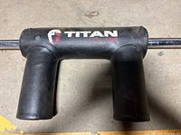 Full view of the black padded shoulder supports on the squat bar with Titan Fitness logo visible.