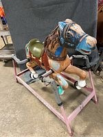 Full view of the vintage Radio Flyer horse mounted on pink metal spring frame with protective wraps on springs, showing paint wear and kid-painted areas.