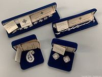 Group shot of two 8-inch bracelets, paisley brooch, and square swirl earrings in original Camrose & Kross blue velvet boxes with certificates
