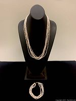 Set display showing the necklace on a bust and the matching bracelet laid flat on a surface.