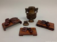Front view of the antique carved stone ritual vessel with three mahogany goldfish carvings on bases arranged around it