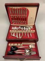Full view of the open flatware chest showing fitted slots for knives, forks, spoons, and serving utensils, all arranged neatly.