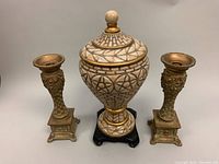 Front view of the urn flanked by the two candleholders on each side, showing full composition and color details