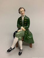 Front view of the Royal Doulton porcelain figurine showing the gentleman seated in historical costume with detailed facial features and green coat.