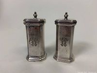 Front view of the two sterling silver salt and pepper shakers showing engraved monogram on each.
