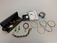 Overview of jewelry items including Monet bangles, Nina Ricci earrings, Michael Kors bracelet, Swarovski necklaces, and other bangles.