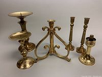 Full group of six vintage brass candleholders on white background