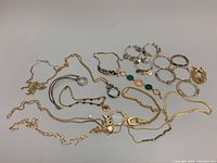 Multiple vintage costume jewelry necklaces and bangles laid out on a white surface, showing majority of pieces and their condition.