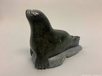 Front angle view of the vintage Inuit soapstone seal carving showing the seal sitting upright on the textured base.