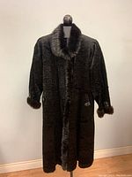Full-length front view of vintage ladies black coat with mink fur collar and cuffs on a mannequin.