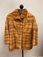 Full view of the mink fur jacket on a mannequin, showing length and overall condition.