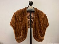 Full view of the vintage ladies mink fur stole on a hanger showing fur texture and shape.