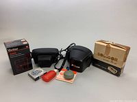 All items laid out: cameras, cases, flash boxes, accessories