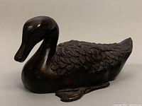 Side profile showing the detailed feathers and smooth bronze finish of the duck sculpture.