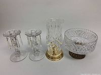 Wide view of the lot including pedestal fruit bowl, two-piece hurricane candleholder with gold-tone base, and pair of hanging prism crystal candleholders.