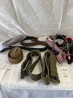 Mixed military and casual belts laid out on white background, showing textures and types
