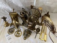 Photo showing a large assortment of brass and bronze items including ram head bookends, brass bird, wall hangings, drinking horn, corkscrew, bell, and other decorative pieces.