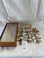 Lot contents including Male Charm display case holding assorted jewellery, pins, brooches, souvenirs with a Cross pen case beside.
