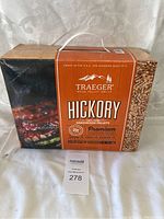 Front view of unopened orange box of Traeger Hickory Hardwood Wood Pellets featuring grilled meat image and branding