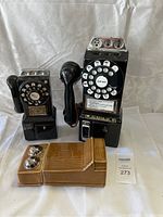 Front view of two black ceramic rotary phone decanters and one tan ceramic box with silver caps.