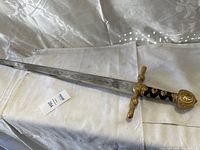 Full length photo of the vintage sword with ornate handle and shiny engraved blade.