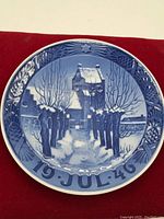 Front view of the blue and white porcelain plate showing a winter scene with house, trees, people, and date '19 JUL 46'