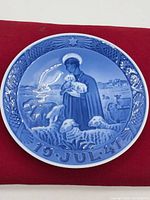 Front view of the 1947 Royal Copenhagen Blue and White Christmas Plate depicting shepherd and sheep with decorative rim and date.