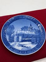 Front view of the blue and white Christmas plate dated 1948, showing a winter church landscape with snow and decorative border with pine cones and stars.