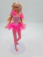 Front view of the Barbie doll in pink ballet outfit showing the full attire and hair style on white display stand.