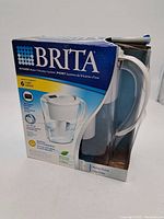 Front view of Brita water filtration pitcher in original packaging showing brand, product image, and capacity details.