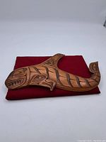 Full front view of carved killer whale panel on red cloth background
