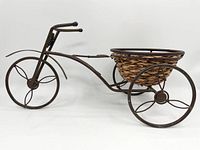 Side angle showing the entire metal frame and woven basket with three spoked wheels.
