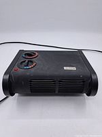 Front view of the black Classic desk heater and fan unit showing vents and dual control dials.