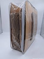 Folded duvet cover and pillowcases inside a clear zippered plastic storage bag with white trim and handle.