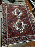 Entire rug laid flat on floor showing full field, medallions, border and fringe