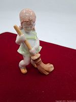 Front view of Herend hand-painted porcelain figurine of a girl holding a broom and sweeping, showing bonnet, dress, and detailed paint.