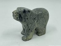 Oblique angled side view showing the form, carving detail and natural stone texture of the soapstone bear sculpture.