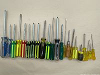 A row of 21 assorted vintage screwdrivers showing various handle colors and sizes arranged side by side on a flat surface.