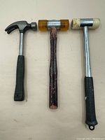 Three hammers arranged side by side on plain surface showing overall condition and types