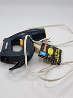 Full view of the Mastercraft electric staple tool with attached electrical cord and pack of Duracell staples.
