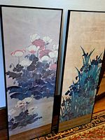 Framed pair of vintage floral art posters leaning against wall, showing full designs and frames.