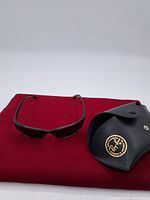 Ray-Ban sunglasses with case on red cloth background showing the overall lot contents.