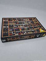 Closed puzzle box showing the front image of many bottles arranged in wooden grids, colorful and detailed.
