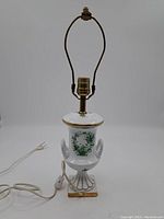 Front view of vintage white porcelain ceramic lamp with wiring and metal harp for shade